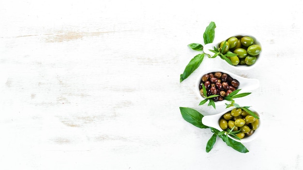 Un conjunto de aceitunas sobre un fondo blanco de madera Vista superior Espacio libre para su texto