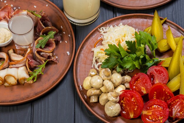 Conjunto de alimentos con costillas de cerdo a la parrilla ensalada de verduras en escabeche y alcohol ilegal sobre fondo de madera negra