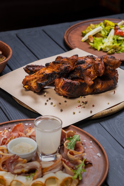 Conjunto de alimentos con costillas a la parrilla sobre fondo de madera negra