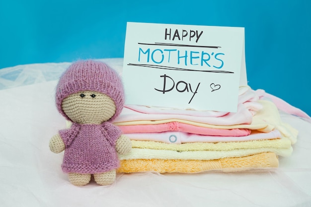 El conjunto de artículos para bebés en la pila, juguetes y tarjetas en blanco sobre un fondo azul. Concepto de feliz día de las madres