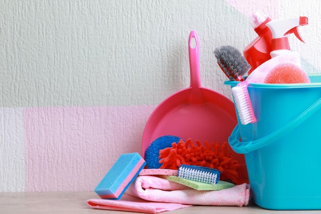 Foto conjunto de artículos de limpieza en la mesa con fondo de color