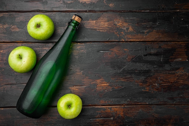 Conjunto de botella de sidra de manzana, sobre fondo antiguo de mesa de madera oscura, vista superior plana, con espacio para copiar texto