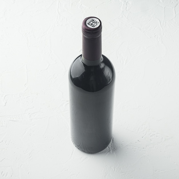 Conjunto de botella de vino, formato cuadrado, sobre mesa de piedra blanca