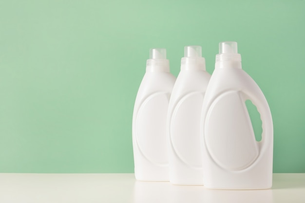 Conjunto de botellas de plástico blanco de detergente líquido para ropa o agente de limpieza o lejía o suavizante de telas. Embalaje de maqueta en blanco para producto de lavado biológico sobre fondo verde. Dia de lavado