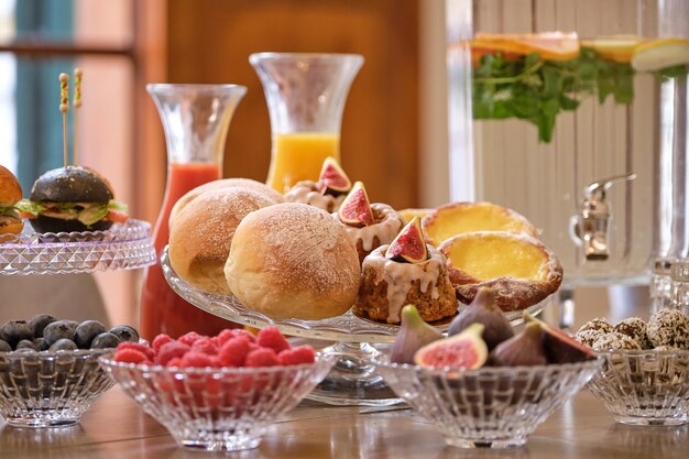 Conjunto de buffet de apetecibles jugos de pastelería y frutas servidos en cuencos de vidrio y colocados en una mesa de madera en la sala de reuniones