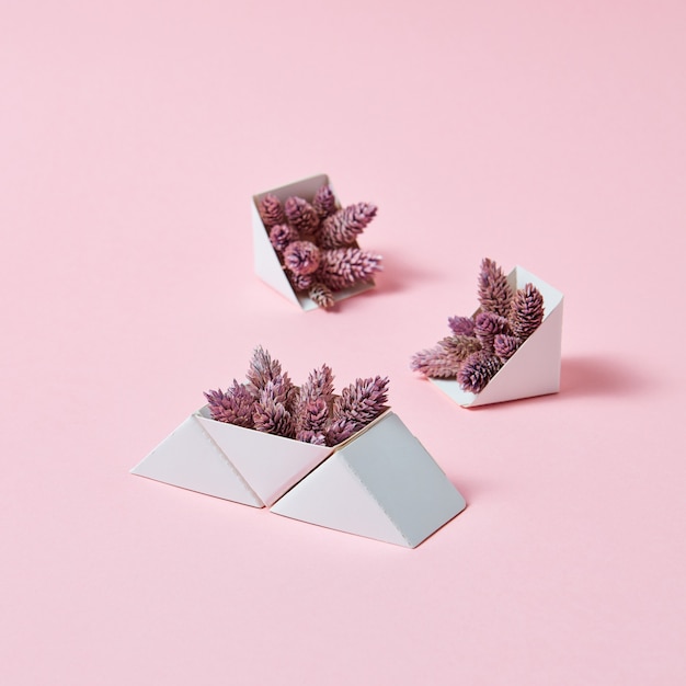 Un conjunto de cajas de cartón triangulares con piñas sobre un fondo rosa con espacio de copia. Una composición creativa