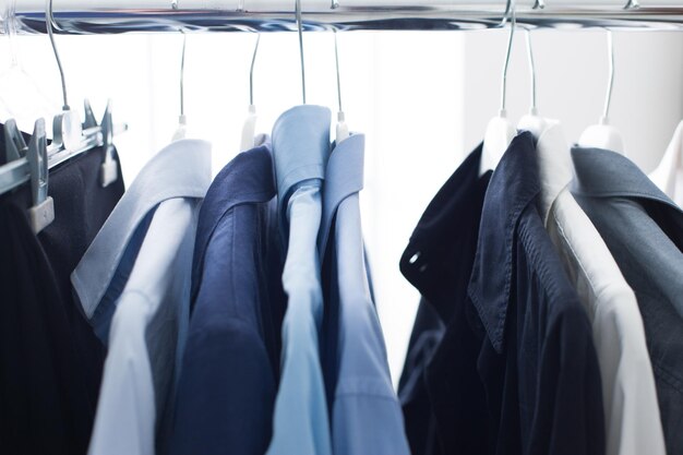 Foto conjunto de camisas elegantes masculinas colgadas en un estante de trajes y vestuario de hombre de negocios