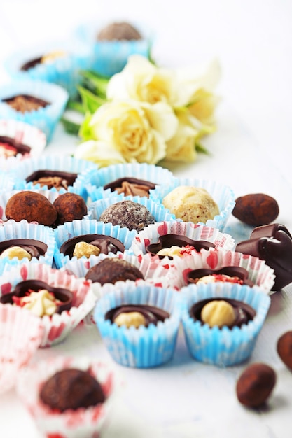 Foto conjunto de caramelos de chocolate con flores sobre un fondo de madera clara, cerrar