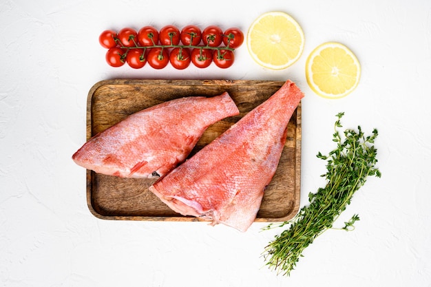 Conjunto de carne de pescado de perca roja, sobre tabla de servir de madera, sobre fondo de mesa de piedra blanca, vista superior plana