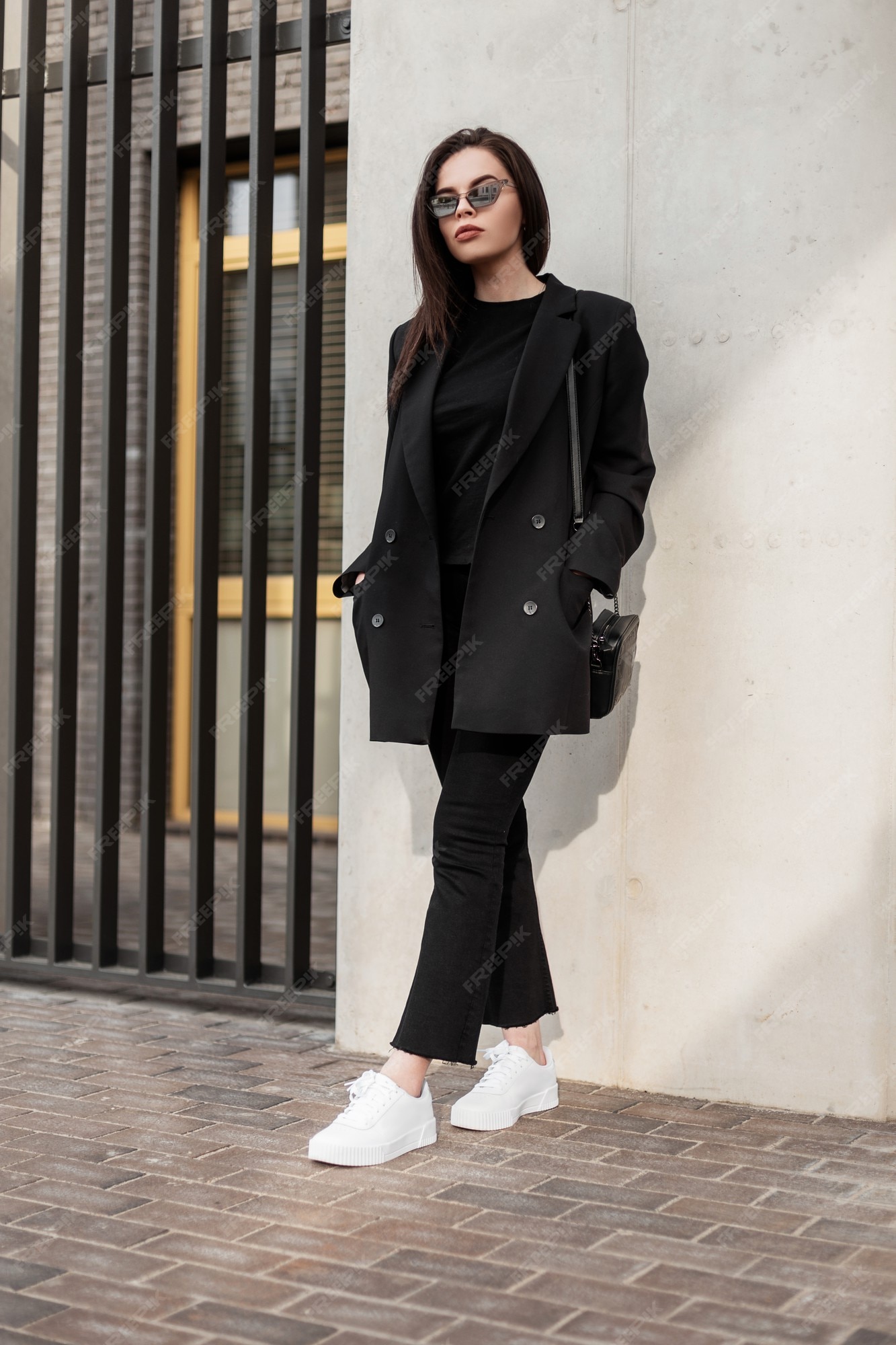 casual juvenil para mujer. mujer joven de moda en camiseta negra hermosa elegante blazer con estilo negro con bolso de moda a la pared en la calle. estilo