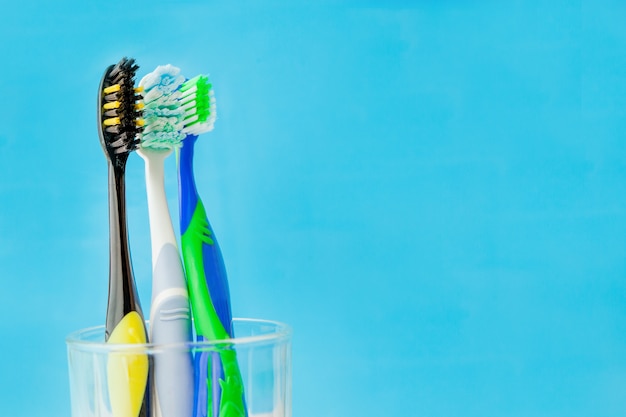 Conjunto de cepillos de dientes en vidrio en la pared azul. Selección de cepillos de dientes conceptuales, espacio de copia