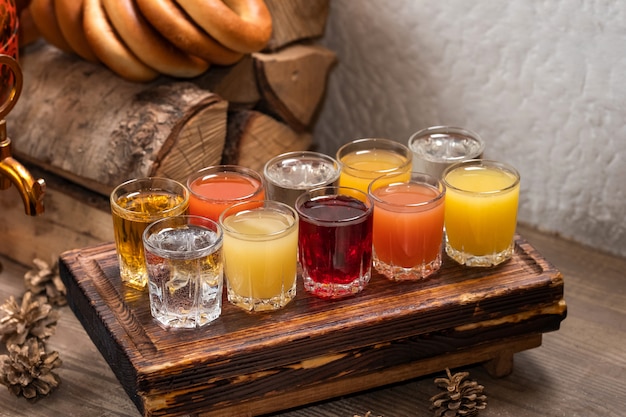 Conjunto colorido de coquetéis alcoólicos em atiradores de copos de shot na mesa de madeira para uma festa alcoólica.