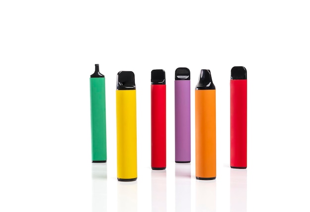 Conjunto de coloridos cigarrillos electrónicos desechables de diferentes formas sobre un fondo blanco.