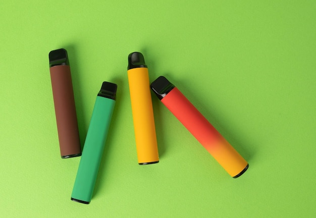 Conjunto de coloridos cigarrillos electrónicos desechables sobre un fondo verde fumar moderno
