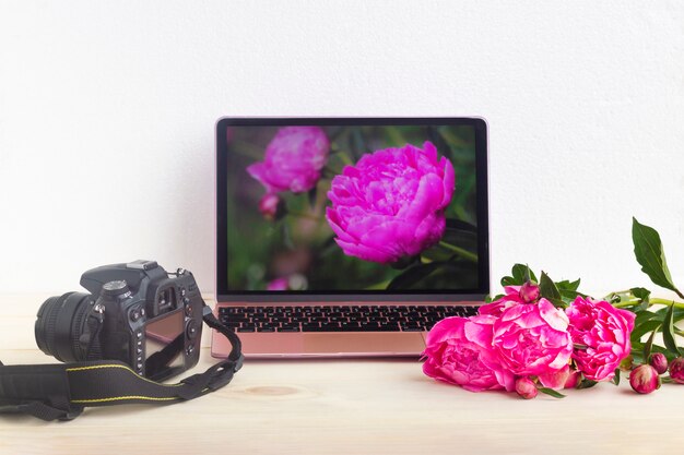 Conjunto com laptop, câmera e flores de peônia. Fotografando flores. Flores em exibição de computador.