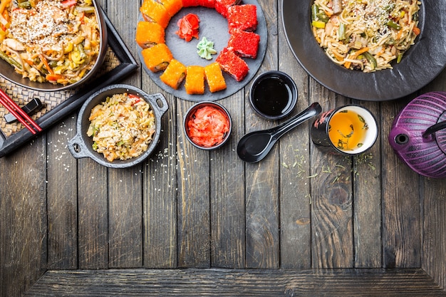 Conjunto de comida asiática servido en madera negra. Cocina china, japonesa y vietnamita, sushi, arroz y fideos.