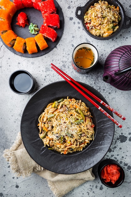 Conjunto de comida asiática servido en piedra gris. Cocina china, japonesa y vietnamita, sushi, arroz y fideos.