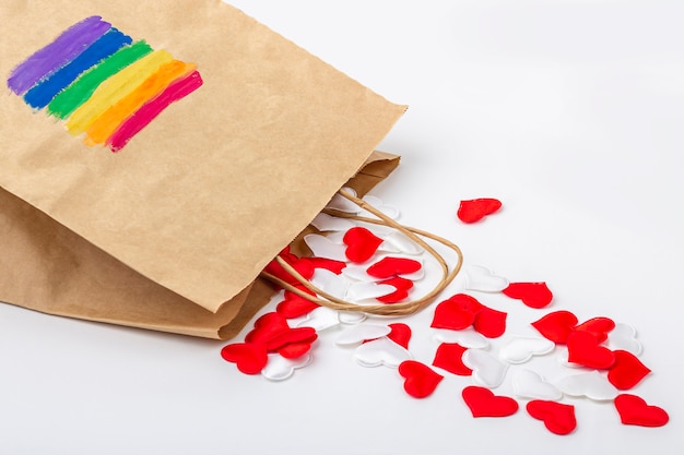 Conjunto de corazones de tela roja y blanca de bolsa de regalo de papel con bandera del arcoíris LGBT pintada en