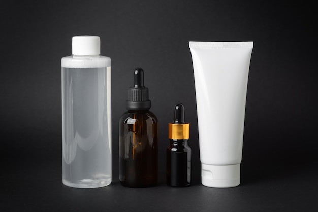 Conjunto de cosméticos de crema de aceite facial y tónico sobre un fondo negro
