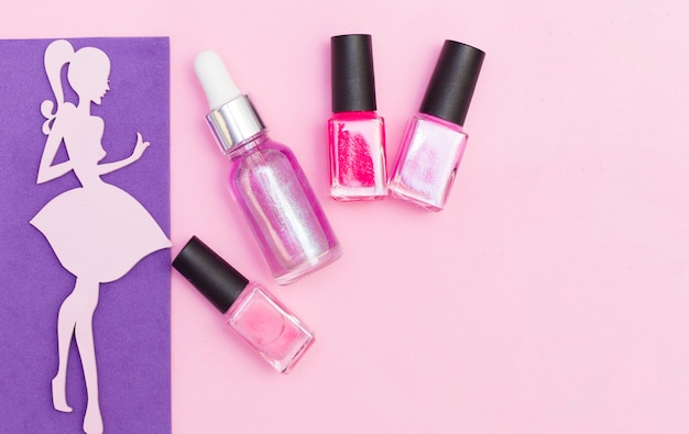 Un conjunto de cosméticos para manicura y pedicura sobre un fondo rosa y morado. Barnices de gel, limas de uñas, tijeras de uñas, empujador, vista superior. Composición para una postal con un lugar para el texto.