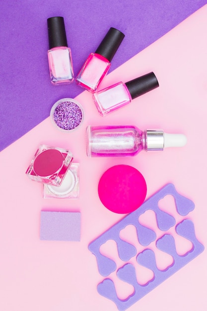 Un conjunto de cosméticos para manicura y pedicura sobre un fondo rosa y morado.
