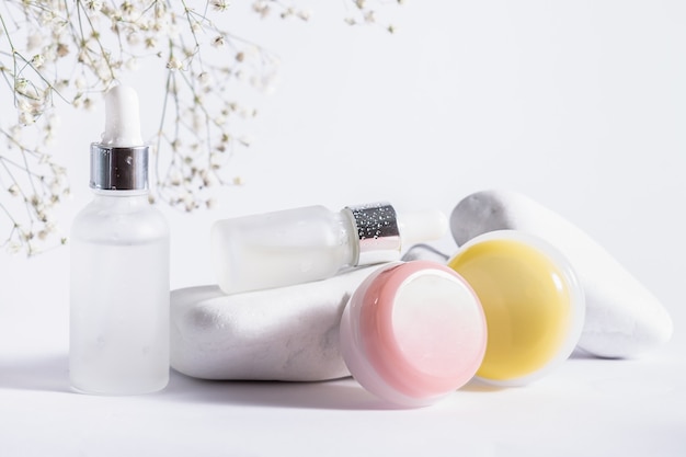 Conjunto de cosméticos orgánicos para el cuidado de la piel y hermosas flores sobre fondo blanco rústico