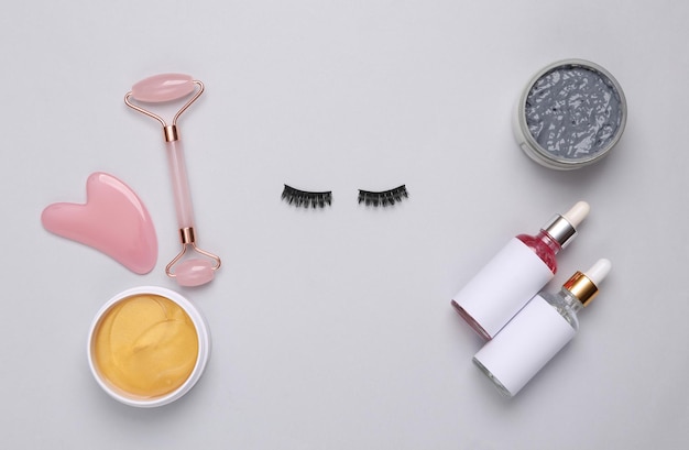 Conjunto para el cuidado facial y pestañas postizas sobre un fondo gris Composición de belleza plana Concepto de elevación del cuidado de la piel