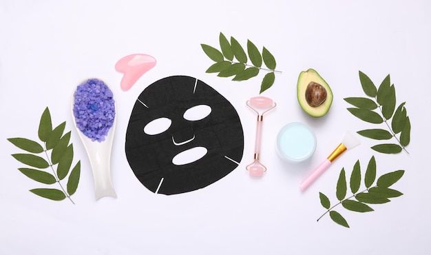 Conjunto de cuidado personal Máscara facial de limpieza negra Masaje facial Guasha raspador de crema Sal y aguacate sobre fondo blanco Cosméticos naturales Belleza plana