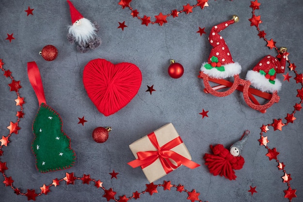 Foto conjunto de acessórios de natal, uma caixa de presente, árvore de ano novo, bolas, coração, óculos em fundo escuro.