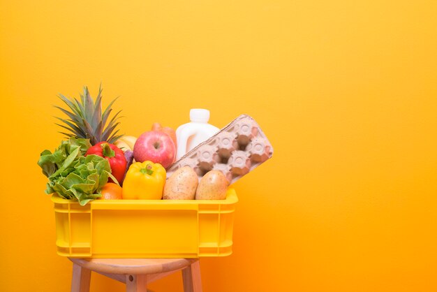 Conjunto de alimentos crus de entrega em caixa de plástico amarelo