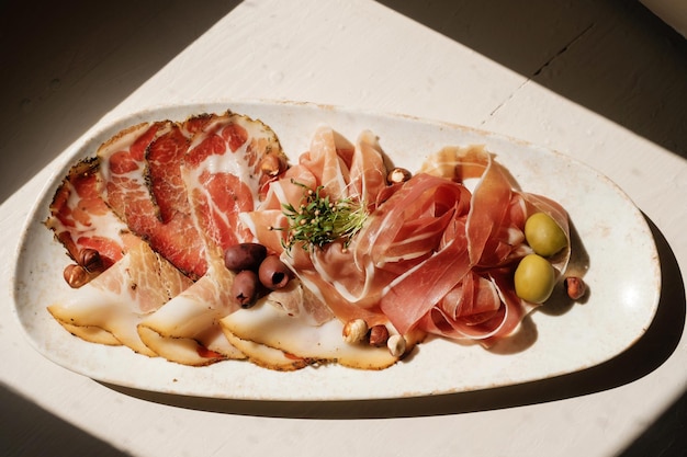 Conjunto de aperitivos de carne com azeitonas de presunto e ervas na vista superior da luz solar