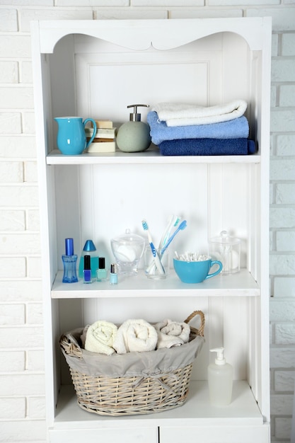 Conjunto de banheiro com toalhas, escovas de dentes e esponjas em uma prateleira no interior leve