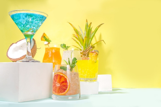 Conjunto de bebidas coloridas de verão. Vários coquetéis e bebidas alcoólicas brilhantes, em copos diferentes, com frutas tropicais