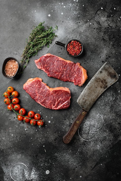 Conjunto de bifes de carne em mármore cru, sobre fundo de mesa de pedra escura preta, vista superior plana, com espaço de cópia para texto