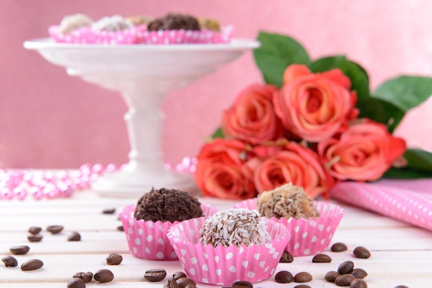 Conjunto de bombons de chocolate na mesa no fundo rosa