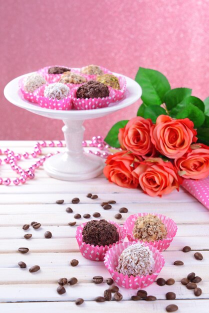 Conjunto de bombons de chocolate na mesa no fundo rosa