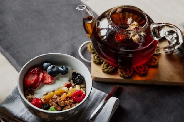 Conjunto de café da manhã, aveia com frutas vermelhas e iogurte, chá preto com rosas, pão