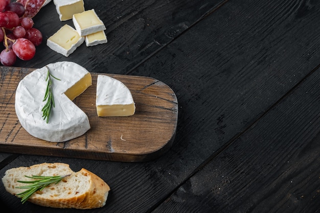 Conjunto de camembert de queijo de fazenda, em mesa de madeira preta