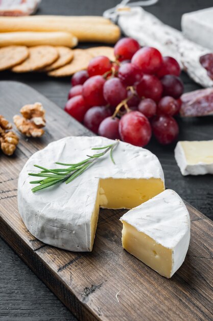 Conjunto de camembert francês macio de queijo normandia, em mesa de madeira preta