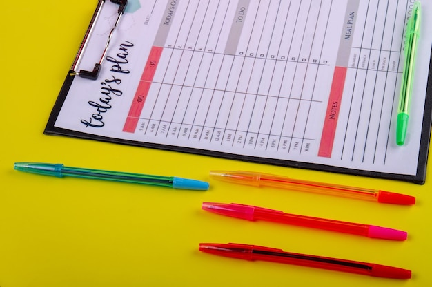 Foto conjunto de canetas coloridas e close-up do calendário da semana. isolado em fundo amarelo.