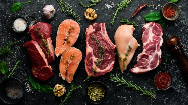 Conjunto de carne Bife de vitela de bife de peixe e peito de frango Vista superior Em um fundo de pedra preta