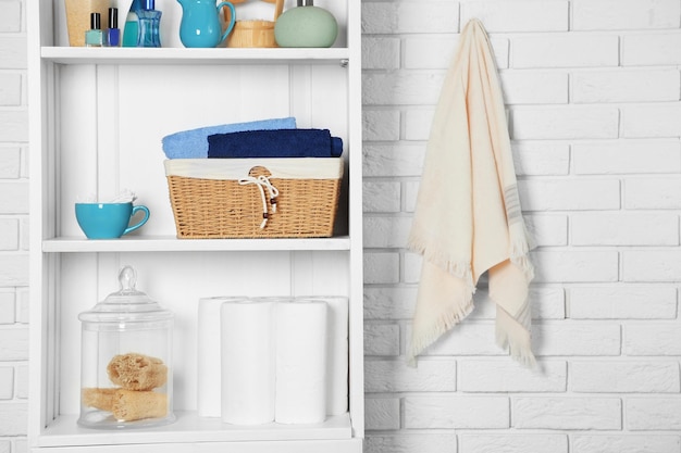 Conjunto de casa de banho com cesto de toalhas e esponjas numa prateleira em interior claro