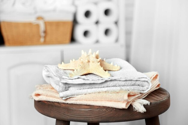 Foto conjunto de casa de banho com toalhas e estrela-do-mar no banco em interior claro