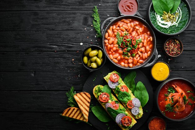 Conjunto de comida em fundo de pedra preta Pratos de legumes de feijão e frutos do mar