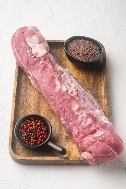 Conjunto de corte de carne de filé de lombo de porco cru, em bandeja de madeira, em pedra branca