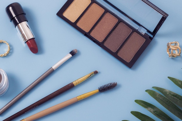 Conjunto de cosméticos femininos com ramo de palma em um fundo azul
