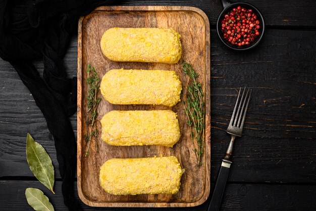 Conjunto de costeleta de frango à milanesa, sobre fundo de mesa de madeira preta, vista superior plana