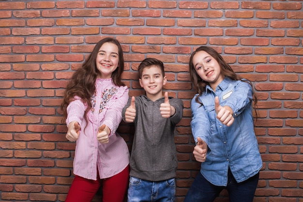 Foto conjunto de crianças pré-adolescentes multirraciais brincalhonas em roupas casuais da moda se divertindo em pé contra um fundo brilhante no estúdio