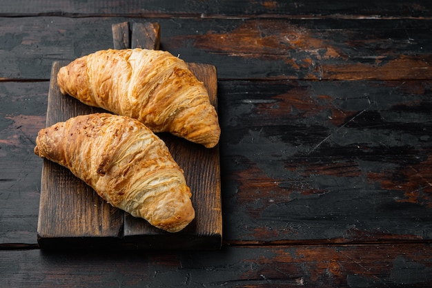 Conjunto de croissant marrom dourado assado caseiro fresco, no fundo da velha mesa de madeira escura, com espaço de cópia para o texto