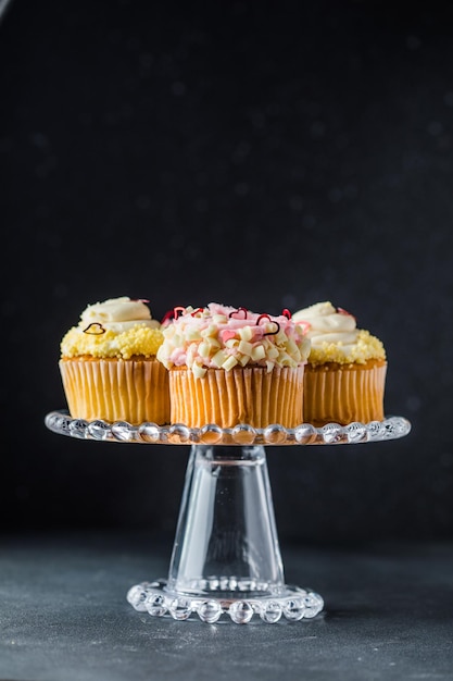 Conjunto de diferentes cupcakes deliciosos em um estande de bolo engraçado